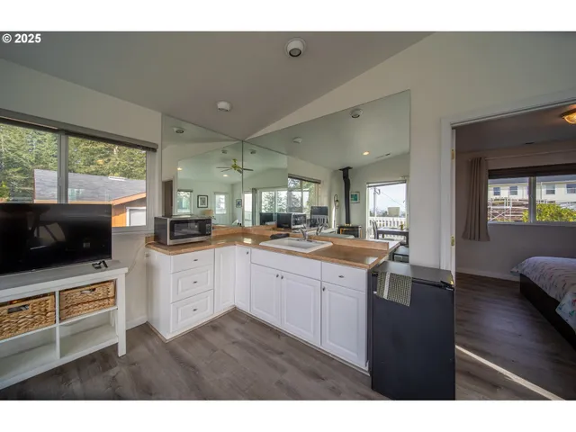 a open kitchen with stainless steel appliances granite countertop a sink a microwave oven a stove and white cabinets with wooden floor