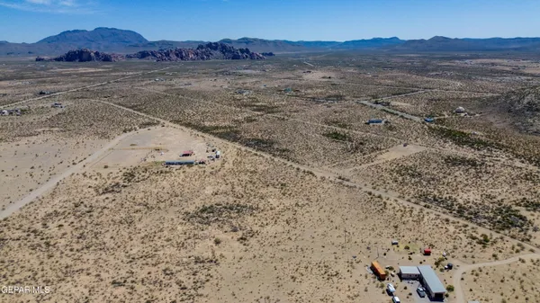 a view of a dry field with mountains in the background
