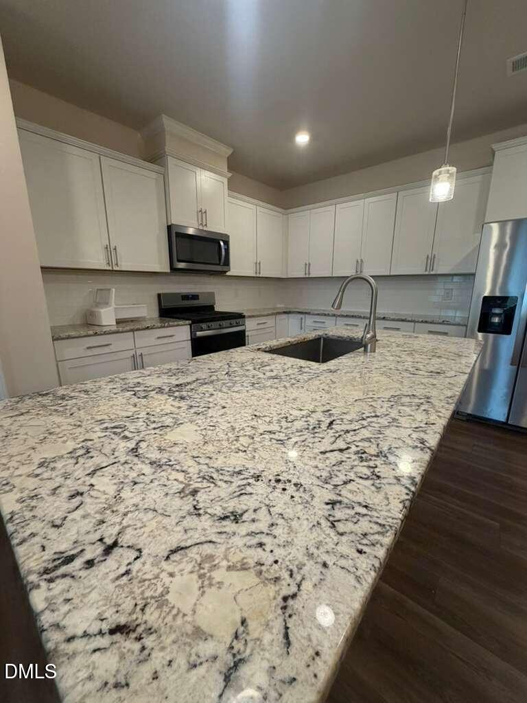 336 Abbots Ml Drive Raleigh, NC 27603 - Photo 4 of 25 a kitchen with kitchen island granite countertop a sink and a stove top oven