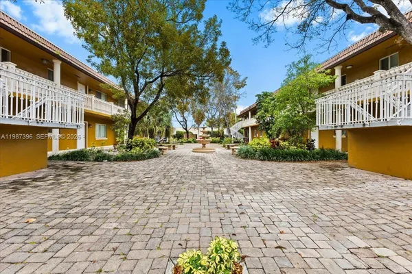 a view of a street with plants and large trees
