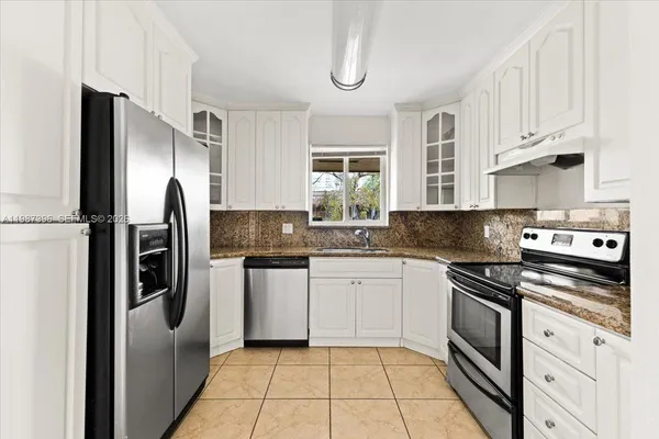a kitchen with stainless steel appliances granite countertop a refrigerator sink and stove
