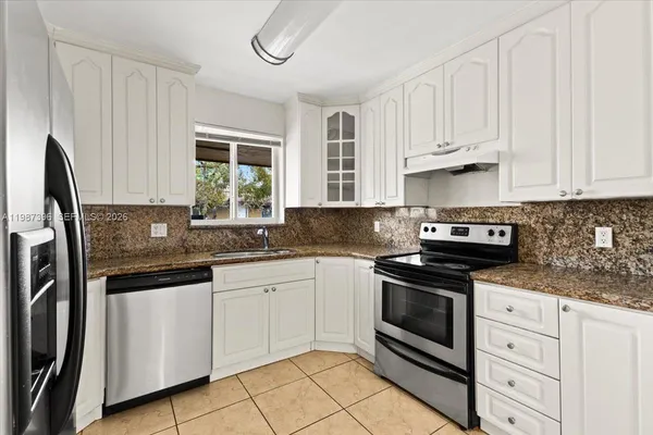 a kitchen with granite countertop white cabinets white stainless steel appliances and a sink