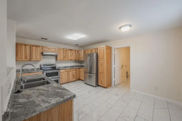 a dining hall with stainless steel appliances granite countertop a sink and a wooden cabinets
