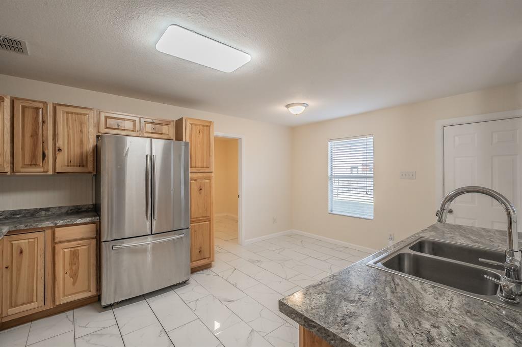 12109 Arbor Lake Road Rhome, TX 76078 - Photo 16 of 33 Kitchen featuring freestanding refrigerator, dark countertops, a textured ceiling, and light marble finish flooring