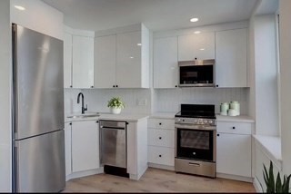 a kitchen with stainless steel appliances a refrigerator stove and white cabinets