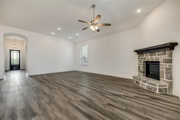 a view of an empty room with wooden floor and a fireplace