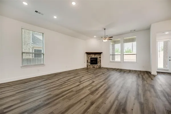 an empty room with wooden floor a ceiling fan and windows
