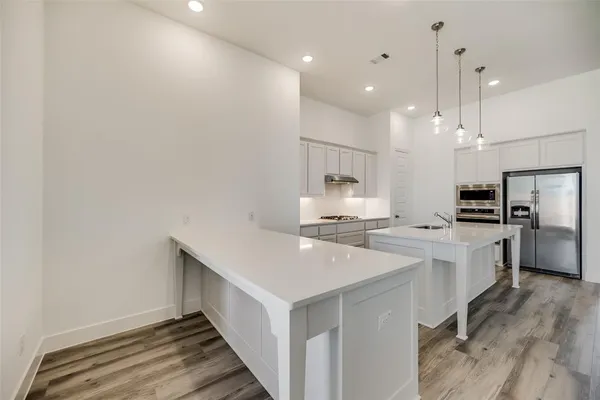 a kitchen with stainless steel appliances a sink a stove a refrigerator and white cabinets