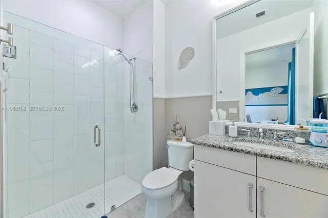 a bathroom with a granite countertop sink toilet and shower