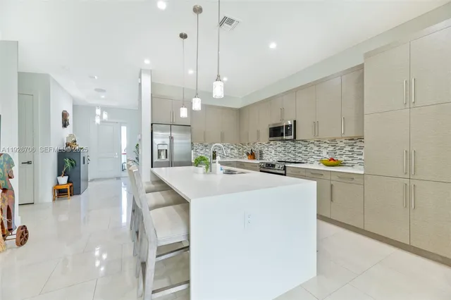 a kitchen with stainless steel appliances kitchen island granite countertop a sink a stove and a refrigerator