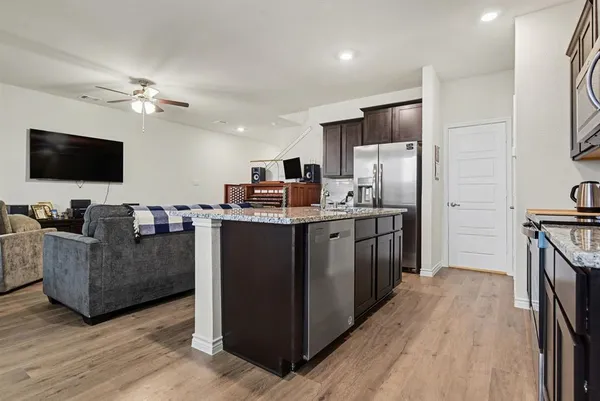 a kitchen with stainless steel appliances kitchen island hardwood floor sink stove and refrigerator
