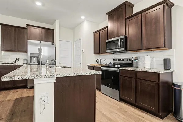 a kitchen with stainless steel appliances granite countertop a sink stove and microwave