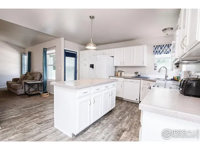 a kitchen with kitchen island granite countertop a sink cabinets and wooden floor