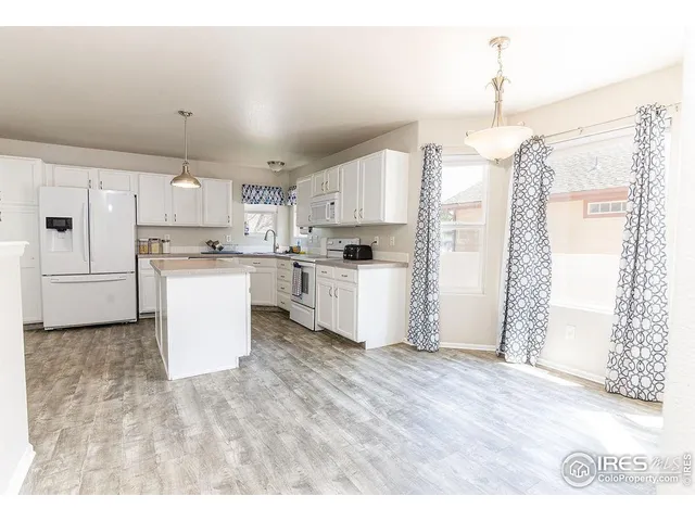 a open kitchen with a refrigerator a stove top oven a sink and white cabinets