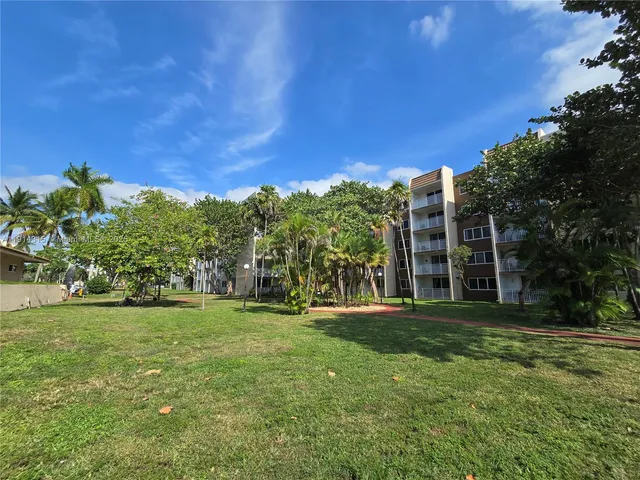 a view of a house with a big yard and large trees