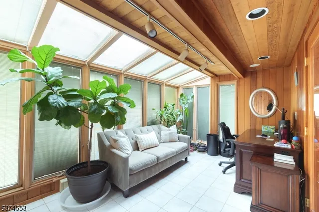 a living room with couches a potted plant and a large window with garden view