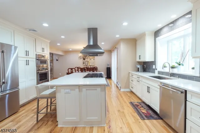 a large kitchen with stainless steel appliances kitchen island a stove a refrigerator a oven and a sink with large countertops