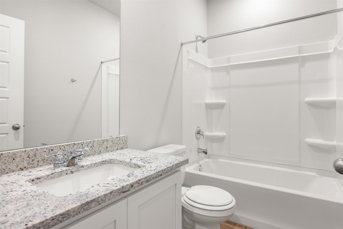 445 Cross Barn Boulevard, Unit B Buda, TX 78610 - Photo 7 of 18 a bathroom with a granite countertop sink a toilet and shower