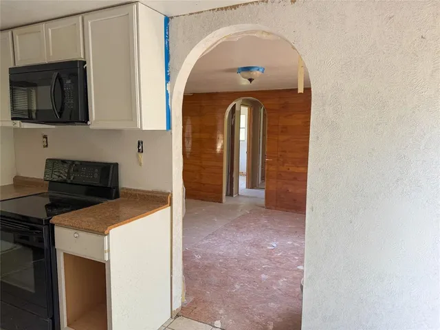 a view of a kitchen with stainless steel appliances granite countertop a stove a microwave and cabinets