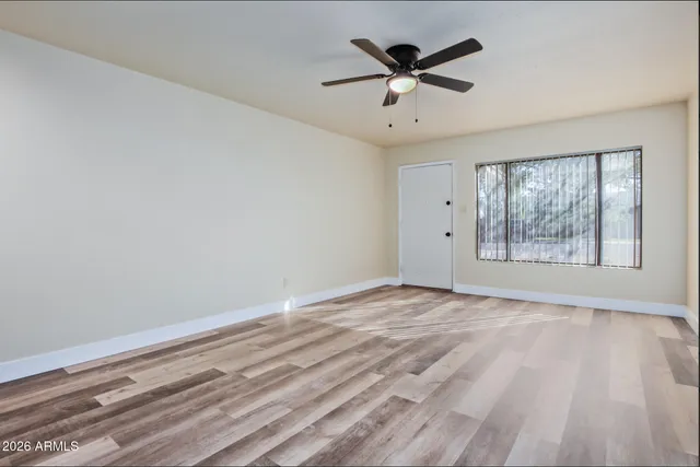 an empty room with wooden floor and windows