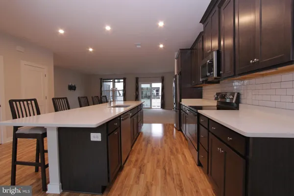 an open kitchen with wooden floor and stainless steel appliances