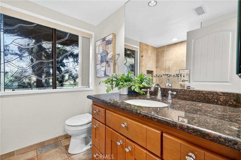 30 Nuevo, Unit 15 Irvine, CA 92612 - Photo 52 of 69 a bathroom with a granite countertop sink a toilet and a large mirror