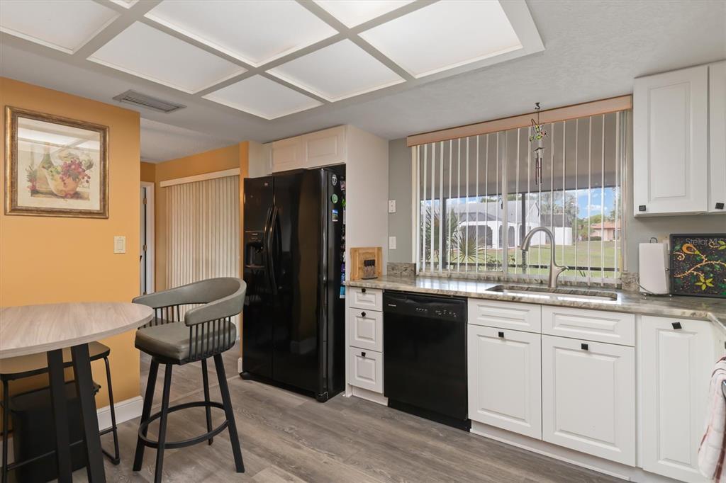 23226 Midway Boulevard Punta Gorda, FL 33980 - Photo 12 of 37 a kitchen with a table chairs refrigerator and window