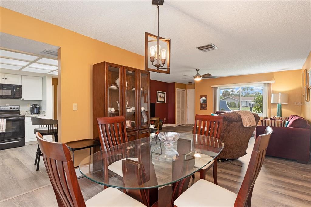 23226 Midway Boulevard Punta Gorda, FL 33980 - Photo 10 of 37 a dining room with furniture a chandelier and wooden floor