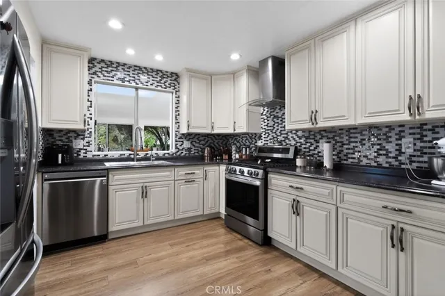a kitchen with stainless steel appliances a refrigerator sink and white cabinets