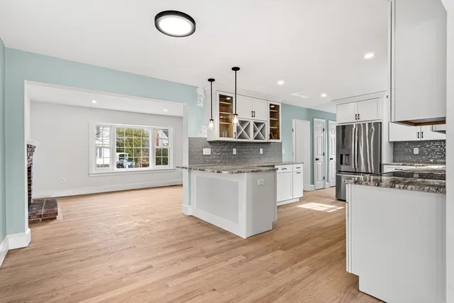 a kitchen with stainless steel appliances a stove top oven a sink a refrigerator white cabinets and wooden floor