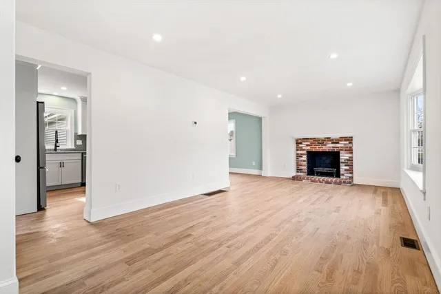 an empty room with wooden floor and fireplace