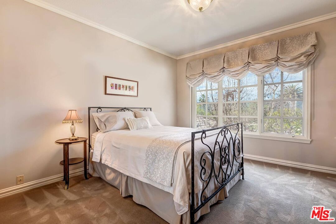 2286 Canyonback Road Los Angeles, CA 90049 - Photo 23 of 40 a bed sitting in a bedroom next to a window
