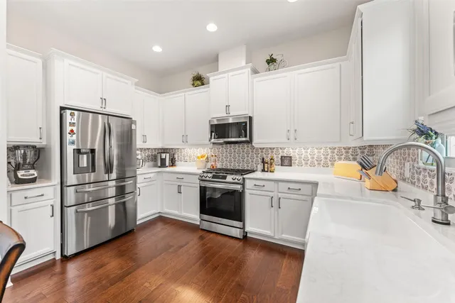 a kitchen with granite countertop white cabinets and stainless steel appliances