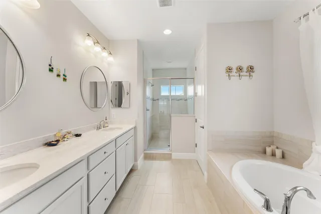 a spacious bathroom with a double vanity sink a mirror a shower and a bathtub