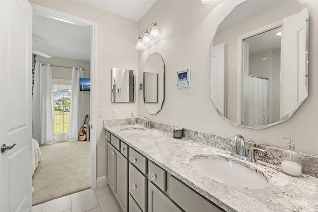 a en suite bathroom with a granite countertop double vanity sink and a mirror