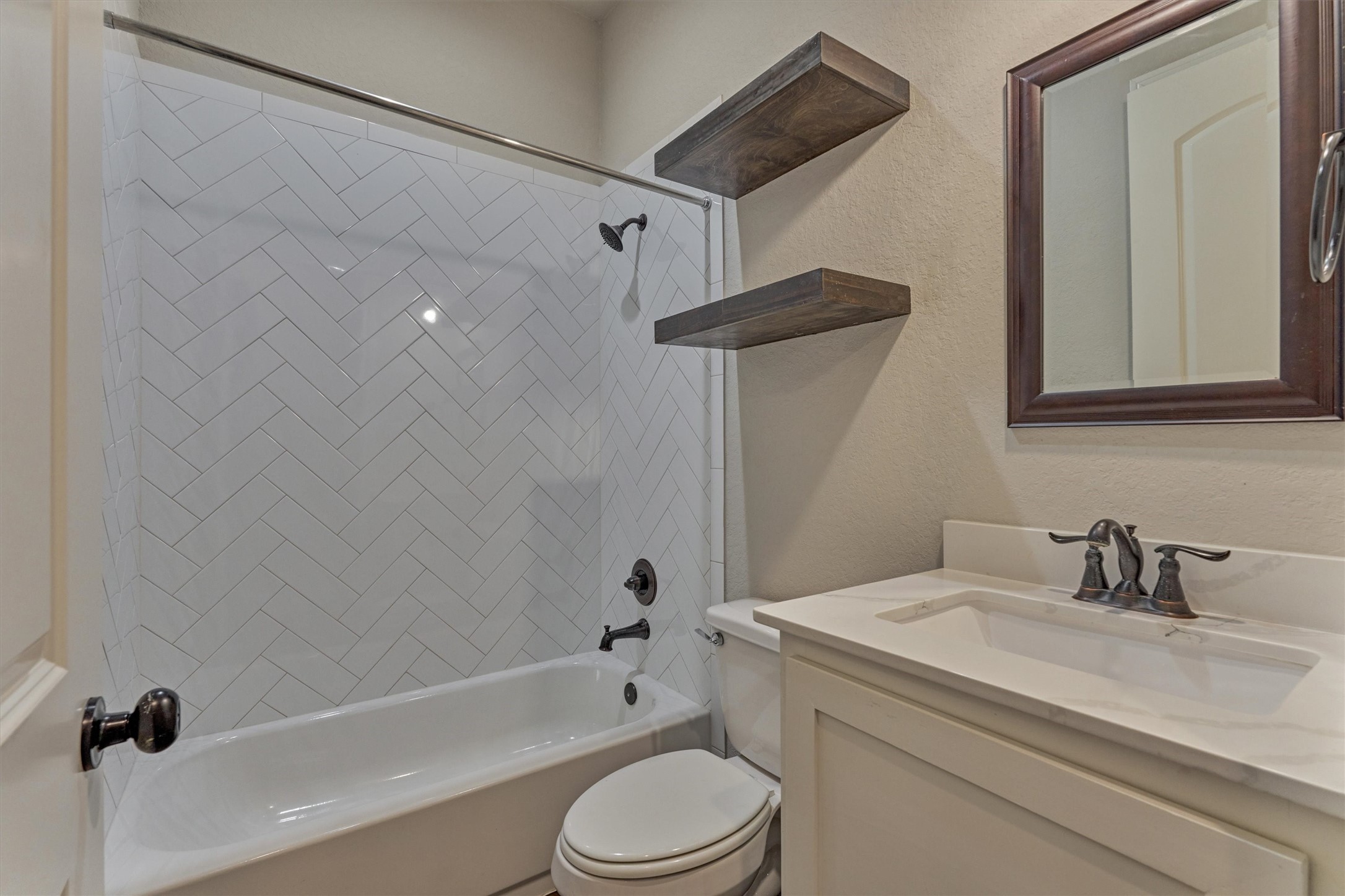 11618 Renaissance Drive Montgomery, TX 77356 - Photo 26 of 49 A full bath in the hallway between two guest bedrooms features wood shelving and a tub/shower with the herringbone pattern wall tile.