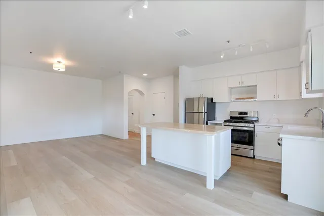 a kitchen with stainless steel appliances white cabinets and wooden floor