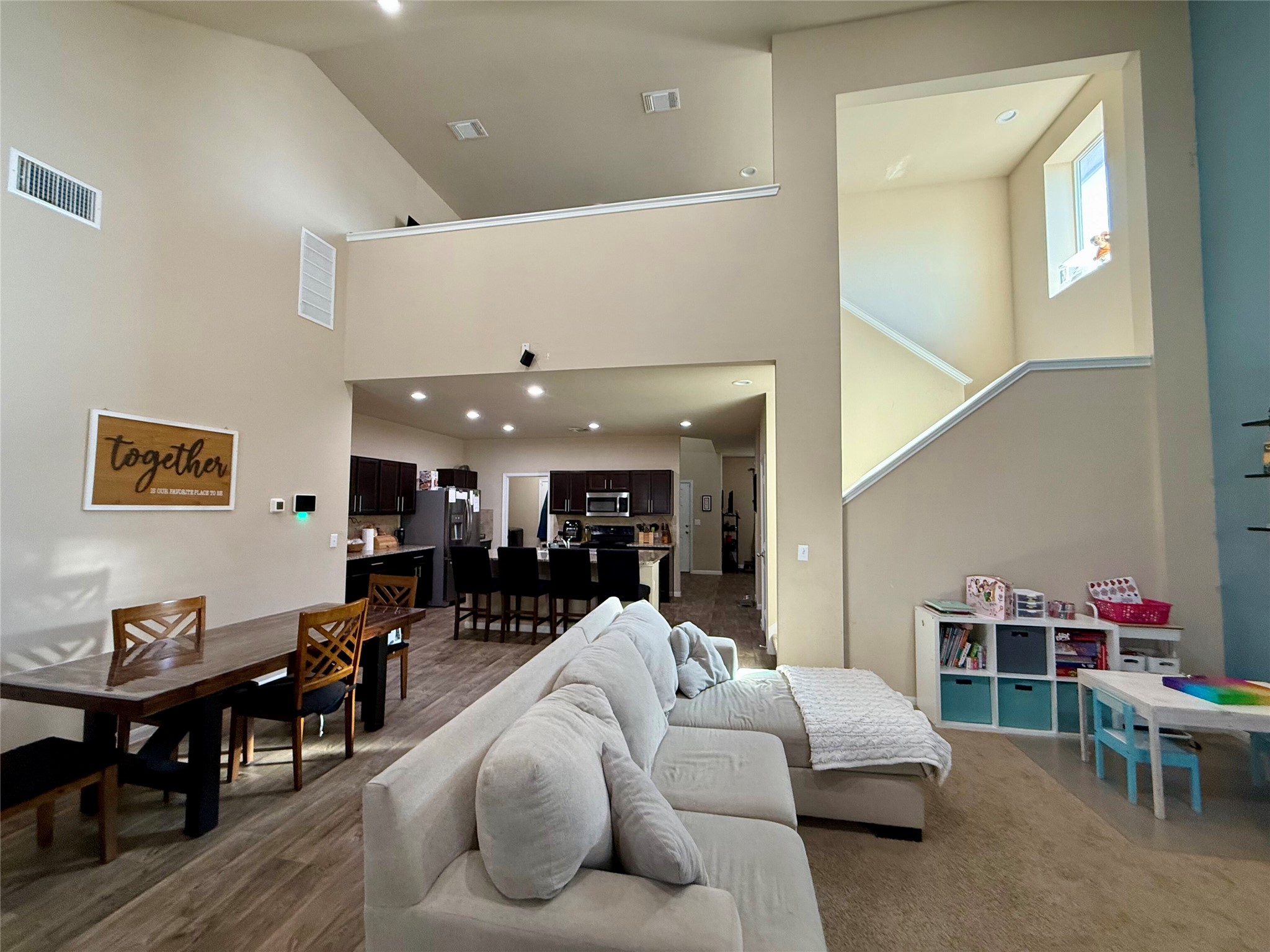 11700 Andesite Road Manor, TX 78653 - Photo 6 of 32 A grand living space opens to a kitchen, featuring high ceilings and a prominent staircase.
