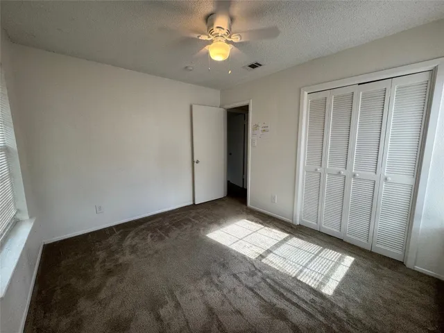 an empty room with windows and fan