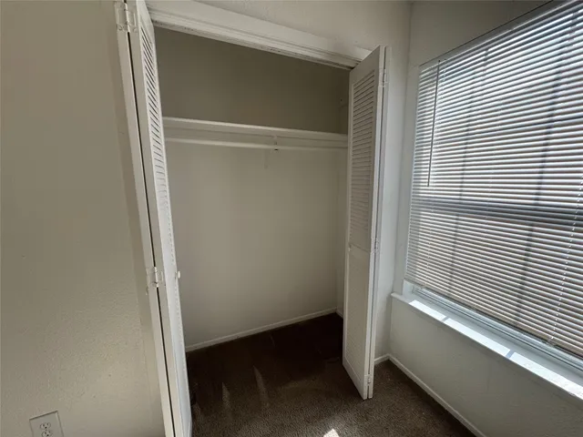 an empty room with windows and chandelier fan