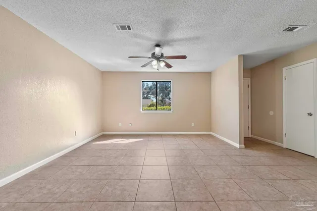 an empty room with windows and chandelier fan