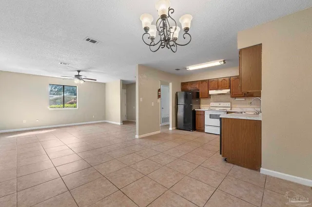 a view of a kitchen with a sink and dishwasher a refrigerator with white cabinets