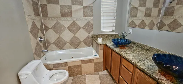 a bathroom with a granite countertop sink and a toilet