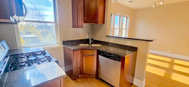 a kitchen with stainless steel appliances granite countertop a stove a sink and a microwave