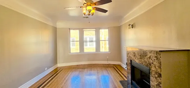 a view of empty room with wooden floor and fan