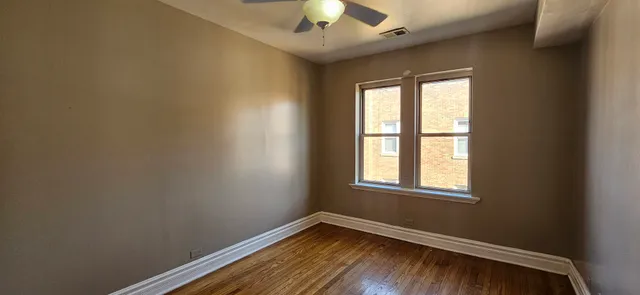 an empty room with a window and a chandelier fan