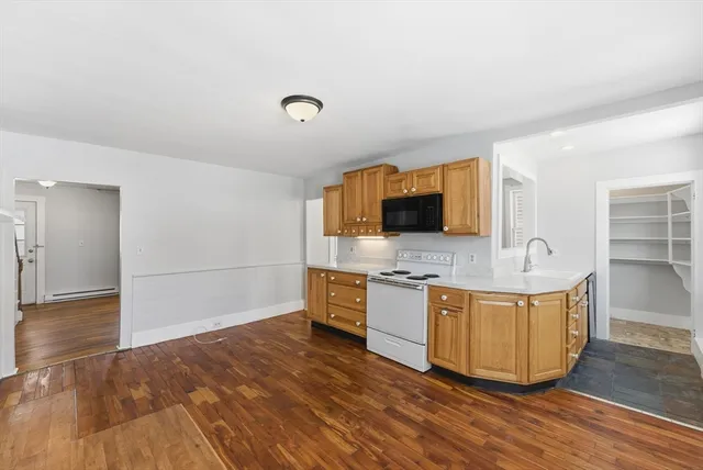 a large living room with stainless steel appliances granite countertop a stove a sink and a flat screen tv