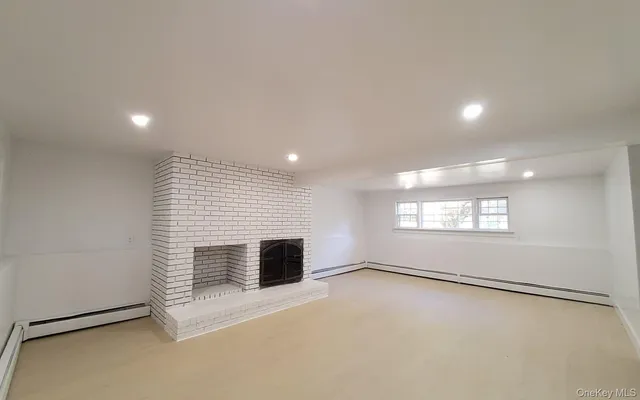 an empty room with windows and fireplace