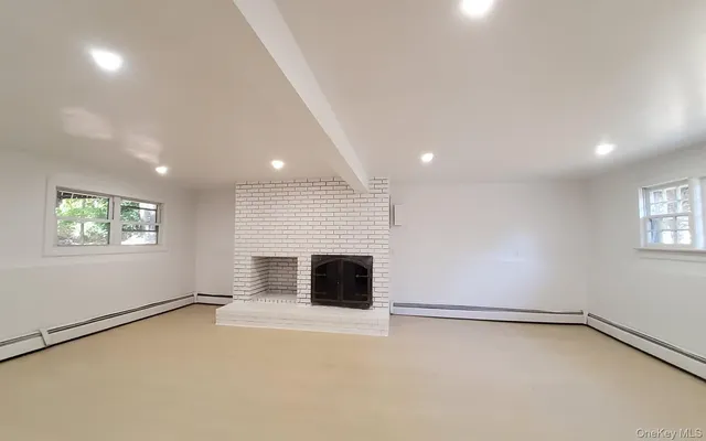 an empty room with windows and fireplace