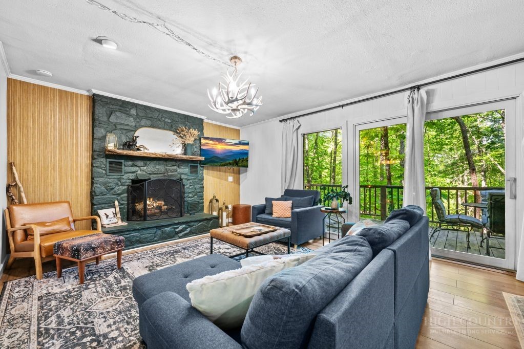 216 Saddle Lane Deep Gap, NC 28618 - Photo 11 of 44 a living room with furniture a fireplace and a floor to ceiling window